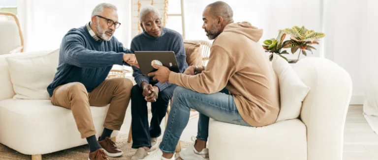 a younger man speaking with an older man and woman while looking at a tabley business formation
