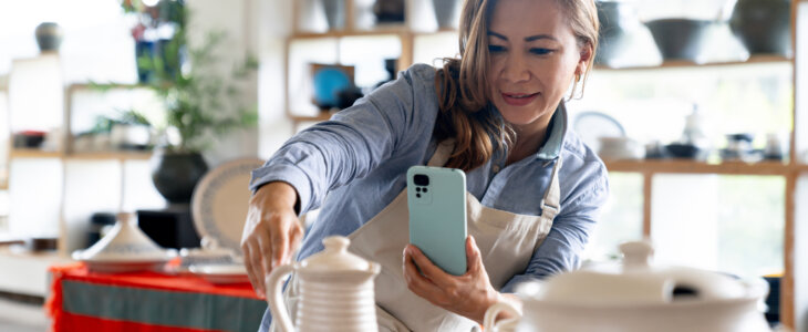 Female small business owner taking a picture of handmade pottery