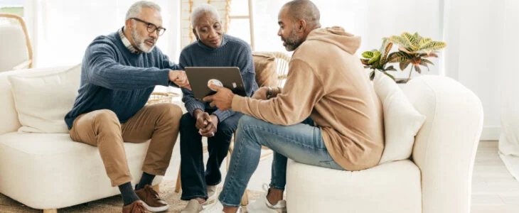a younger man speaking with an older man and woman while looking at a tabley business formation
